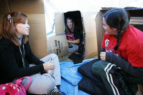 2 girls sitting inside of their temporary box homes for the night during Shantytown Sunday